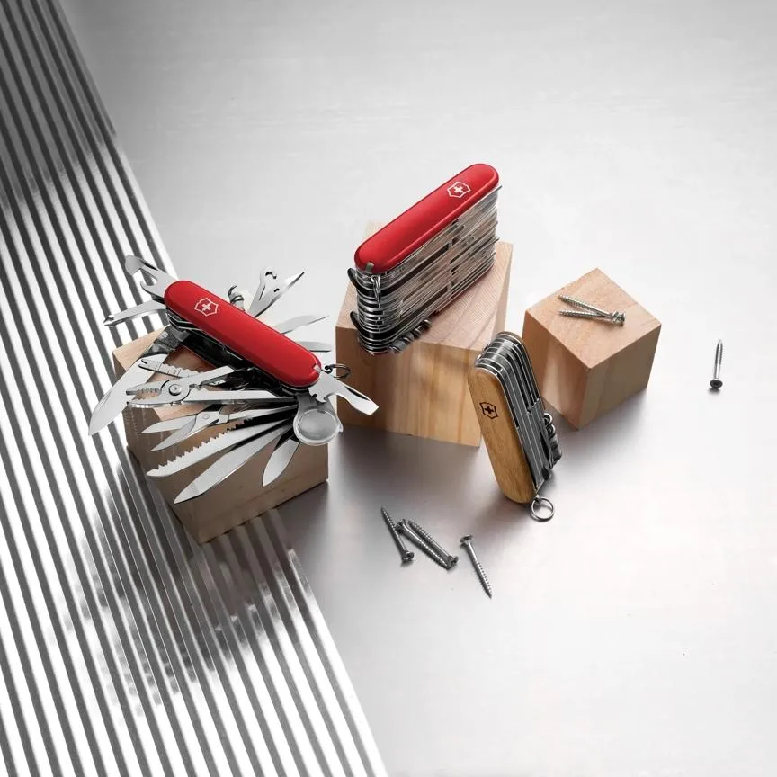 Three Victorinox Ranger 55 Grip multitools are displayed on wooden blocks, with one fully open showing its tools and two closed.